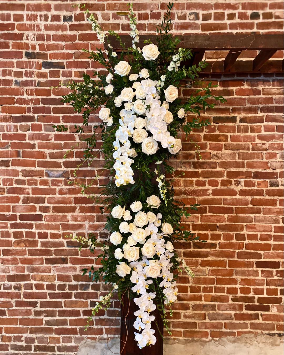 rose and orchid floral arrangements on wedding arch