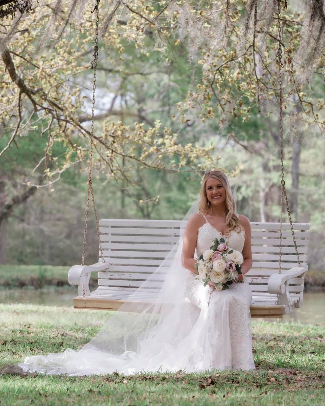 bride sitting on white tree swing