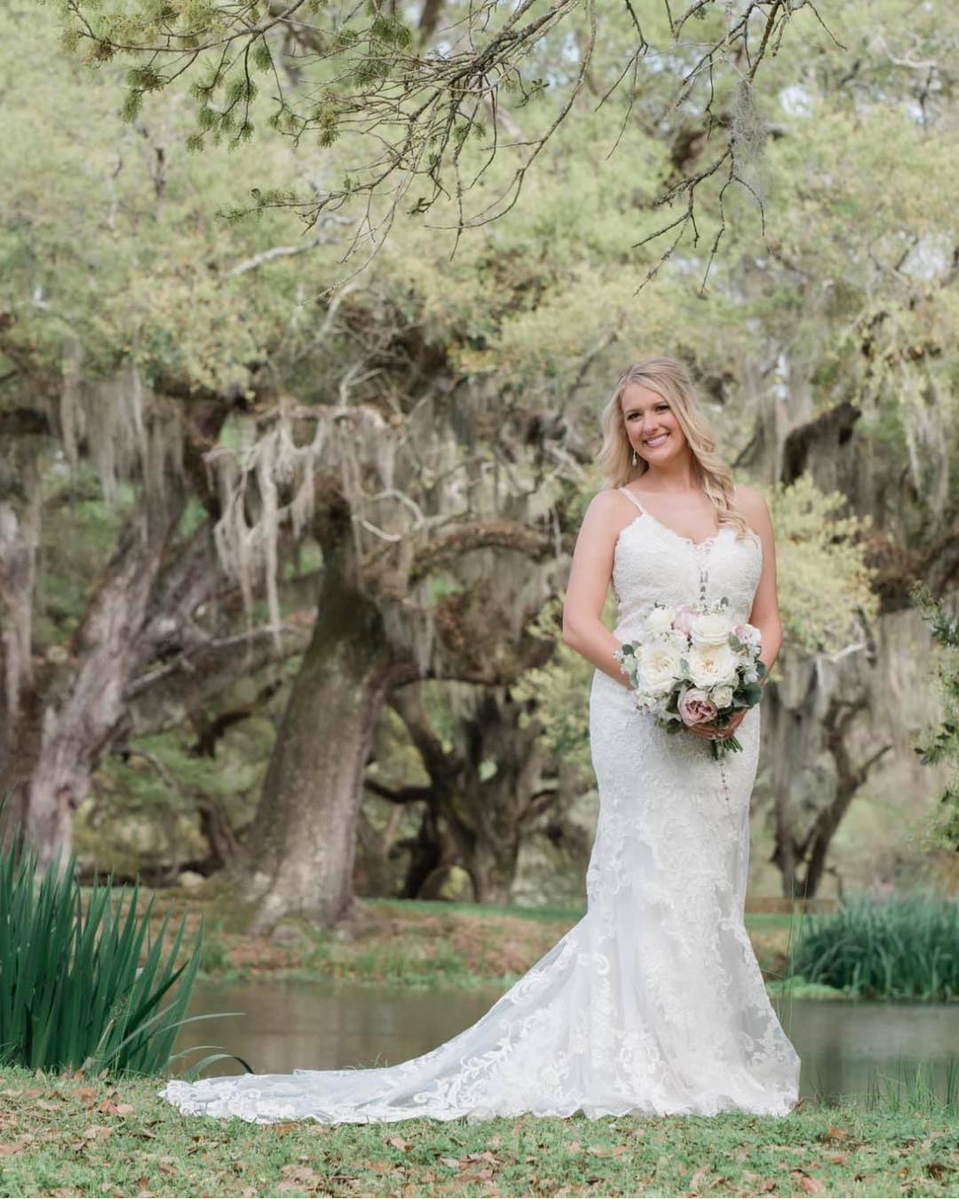 bride holding white bouquet under trees with spanish moss