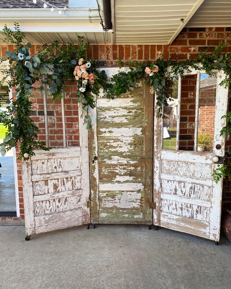 wedding backdrop made from antique doors with flowers and greenery