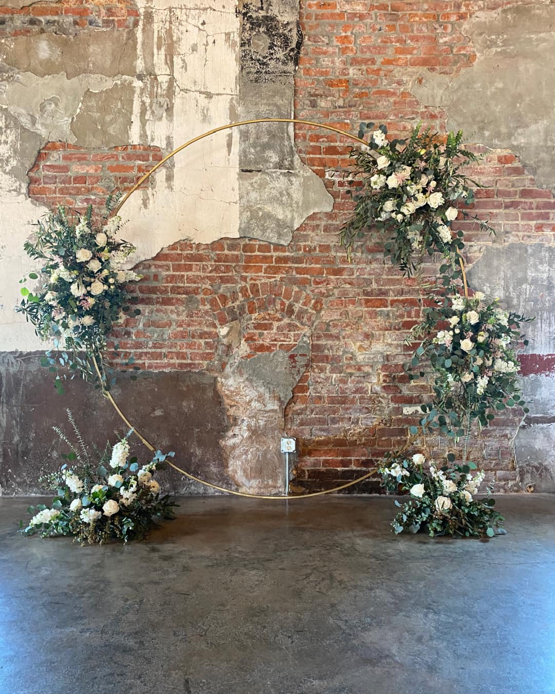 gold metal arch with white floral arrangements attached for wedding