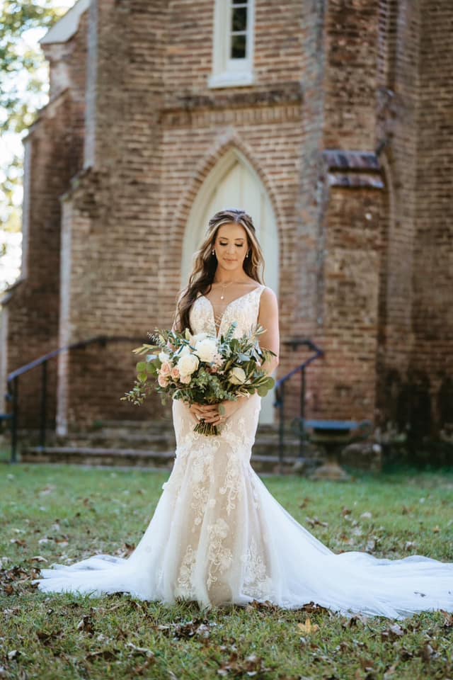 bride holding bridal bouquet in front of old brick church